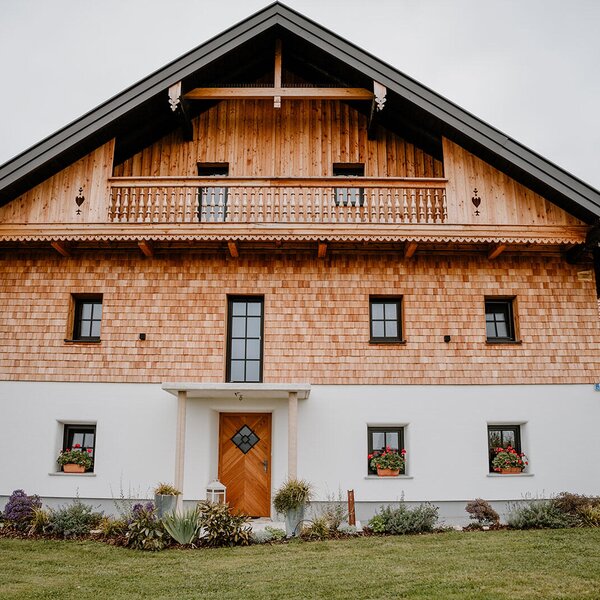 Exterior view of the Bed and Breakfast featuring a wooden facade, white plaster, a balcony, and a front garden.