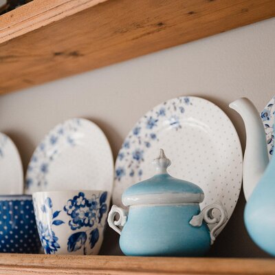 Blue and white ceramic dishes on a wooden shelf in the farmhouse.