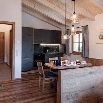Kitchen and dining area in the farmhouse with a modern kitchen unit, dining table, and wooden beamed ceiling.