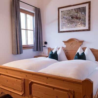 Bedroom in the farmhouse featuring a wooden double bed, bedside tables, and a window with curtains.