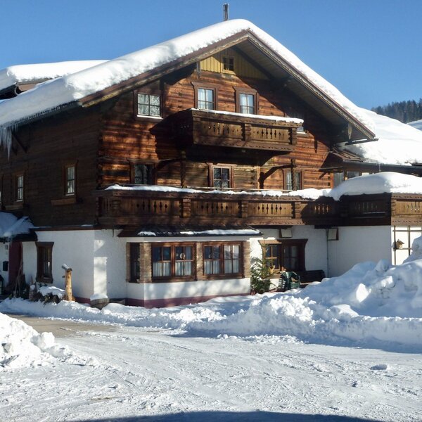 The exterior of the Farm House, a wooden building with multiple balconies, covered in snow during winter.