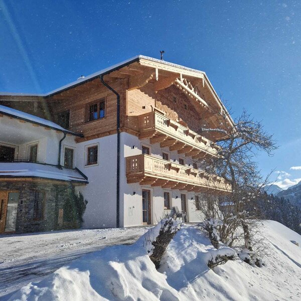 Exterior view of the Bauernhof in winter, featuring traditional architecture, wooden balconies, and a snow-covered landscape.