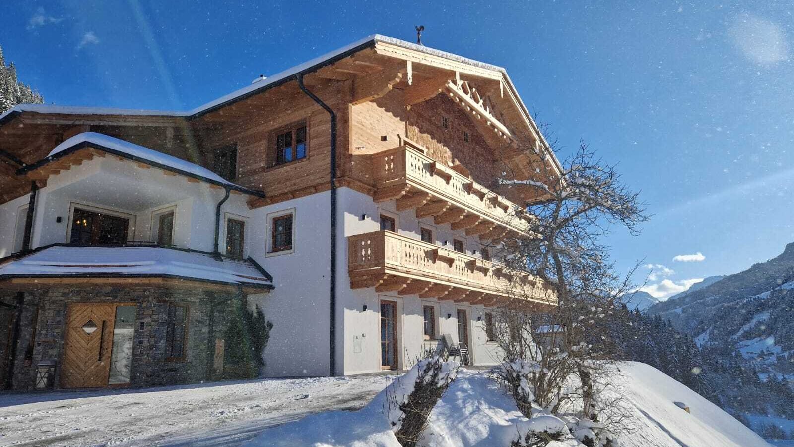 Exterior view of the Bauernhof in winter, featuring traditional architecture, wooden balconies, and a snow-covered landscape.