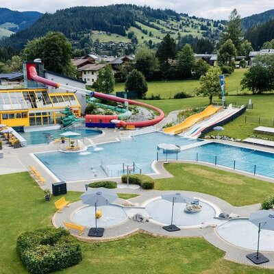 The outdoor swimming complex features multiple pools, water slides, and sunbathing lawns, offering recreation for guests of the Bauernhof.
