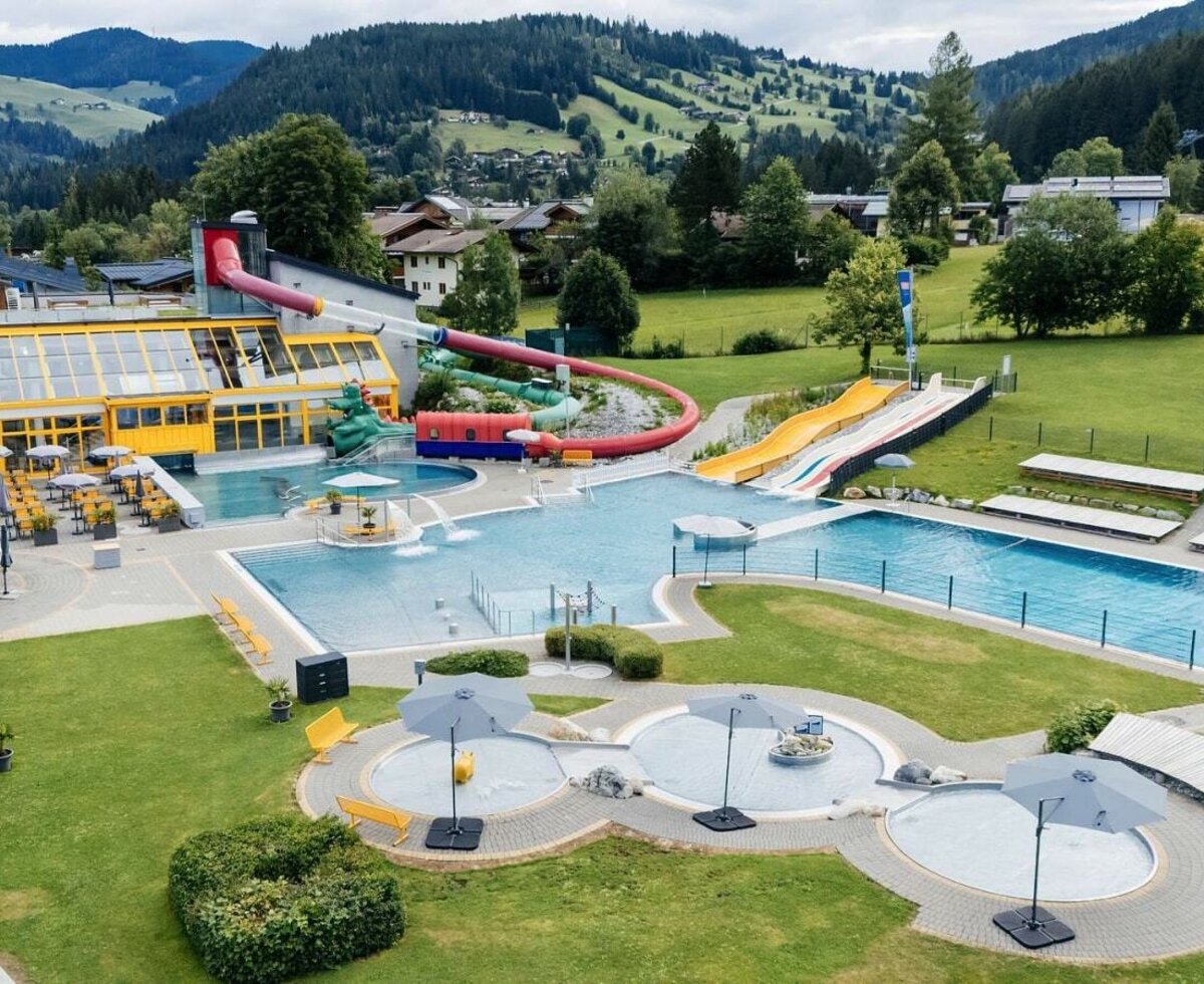 The outdoor swimming complex features multiple pools, water slides, and sunbathing lawns, offering recreation for guests of the Bauernhof.