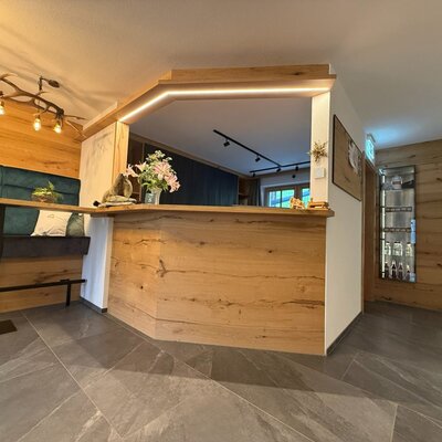 The reception area of the farmhouse with a wooden counter, seating bench, and display cases.