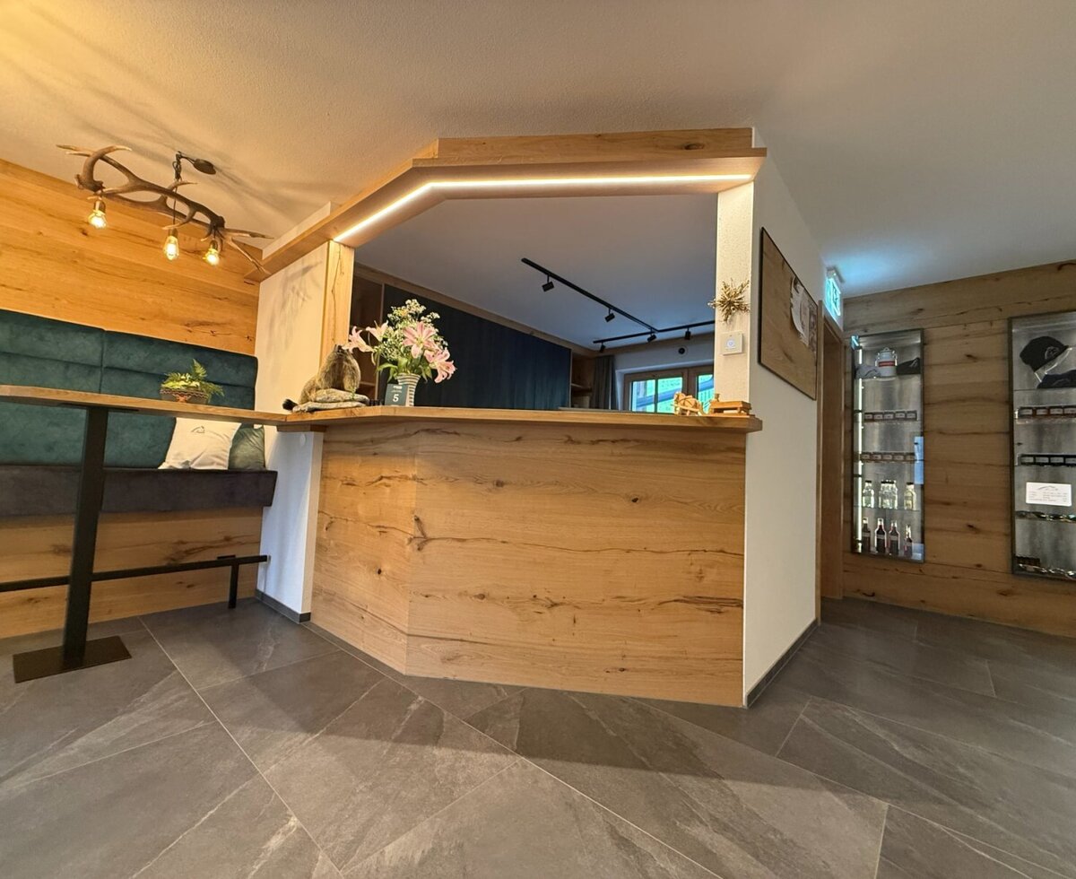 The reception area of the farmhouse with a wooden counter, seating bench, and display cases.