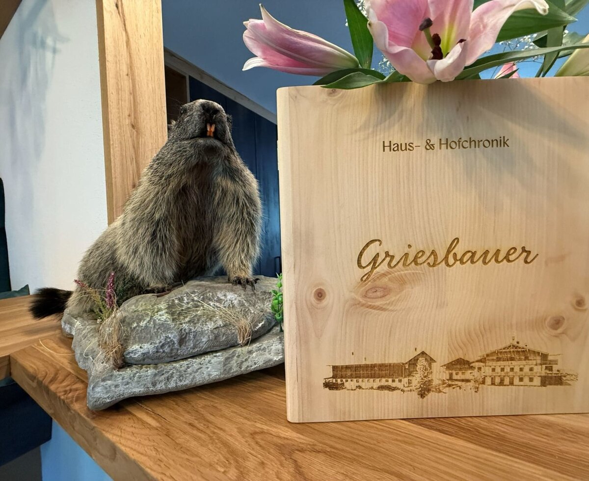 House & Farm Chronicle of the Griesbauer Bauernhof, a wooden sign with engraving and marmot decoration.