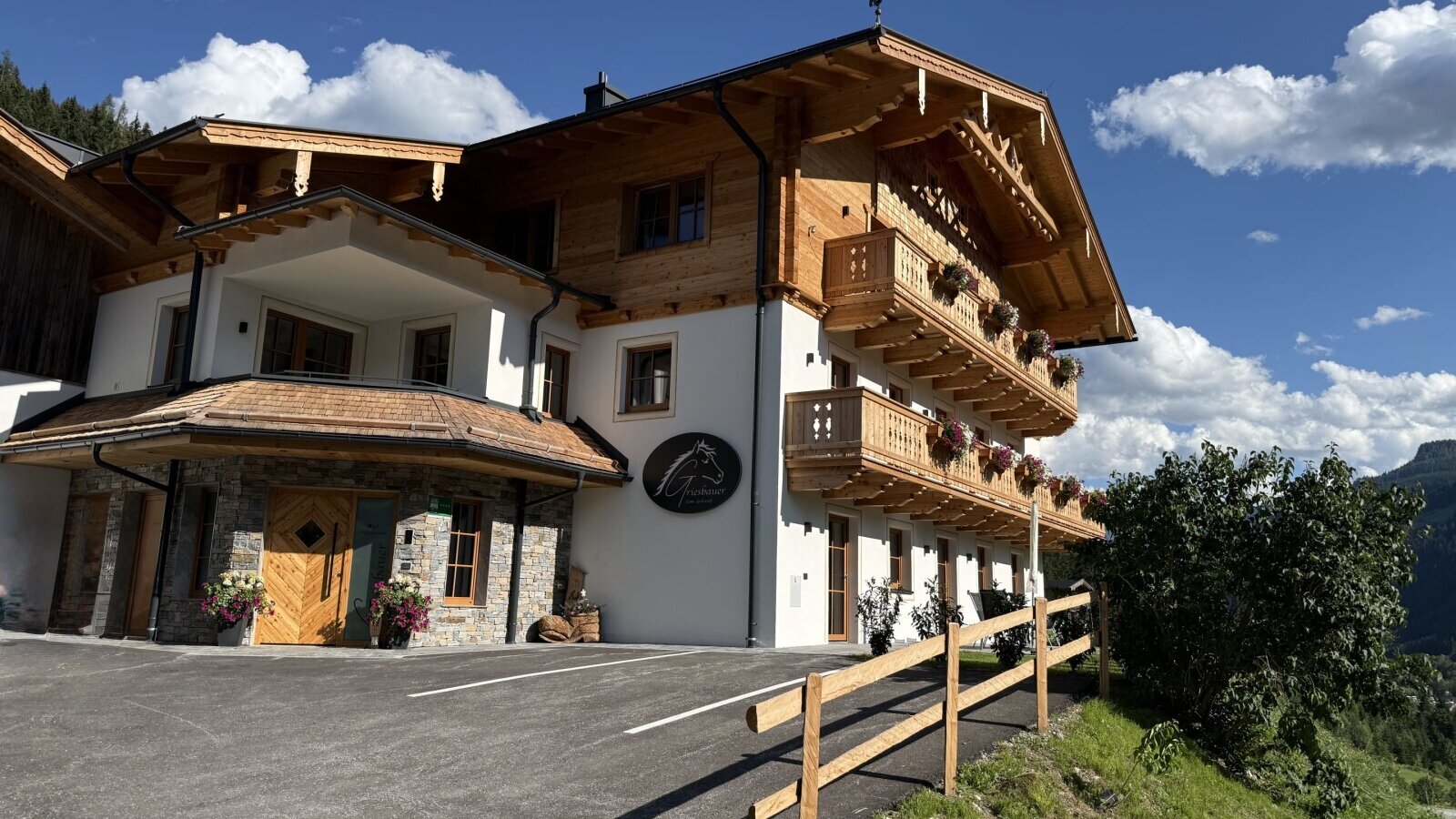The inviting farmhouse featuring a traditional wooden facade and flower-filled balconies under a bright blue sky.