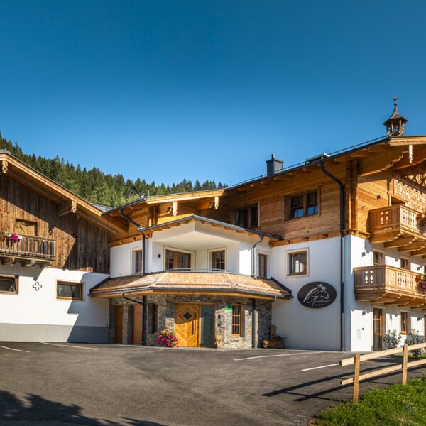 The inviting farmhouse featuring traditional wooden balconies set against a scenic mountain backdrop.