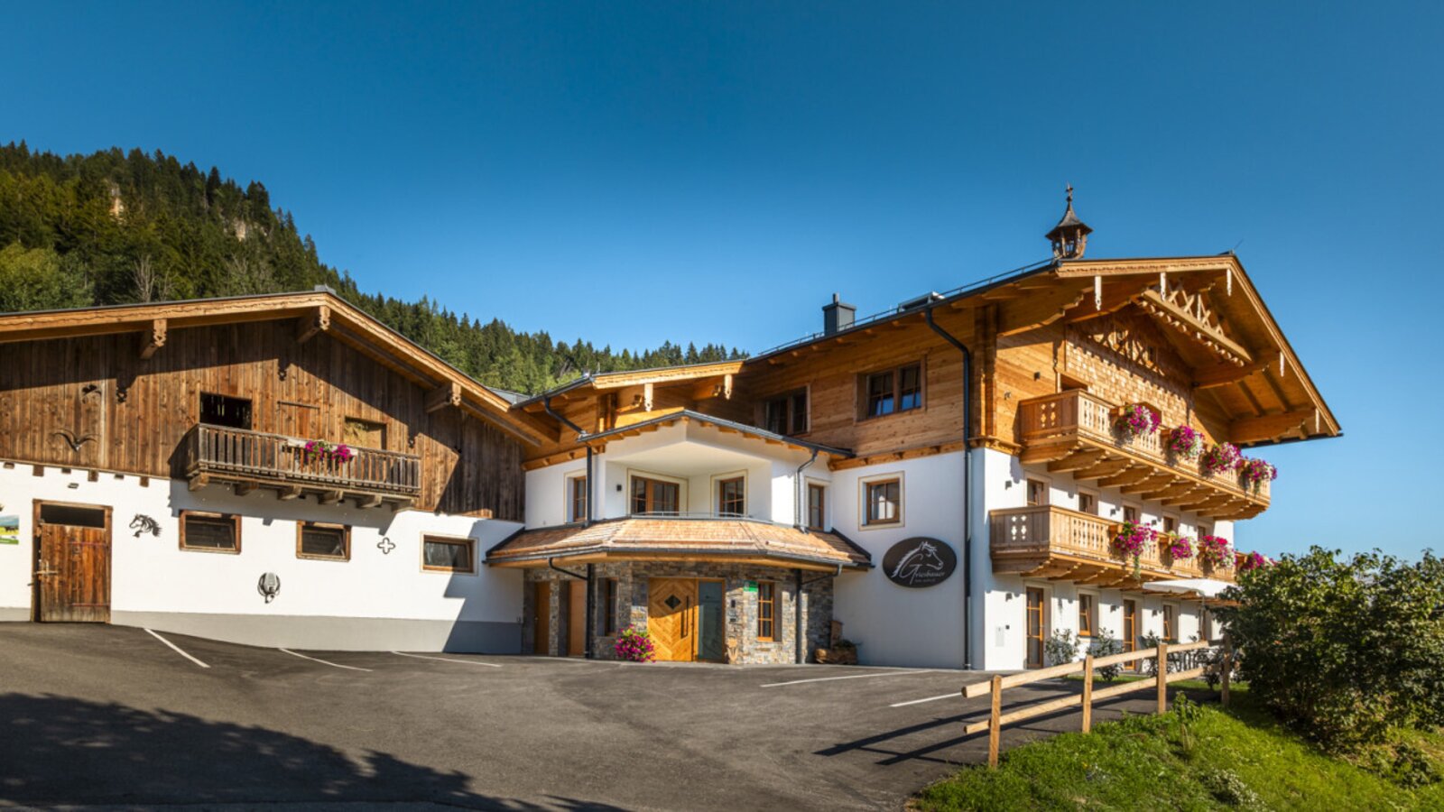 The inviting farmhouse featuring traditional wooden balconies set against a scenic mountain backdrop.
