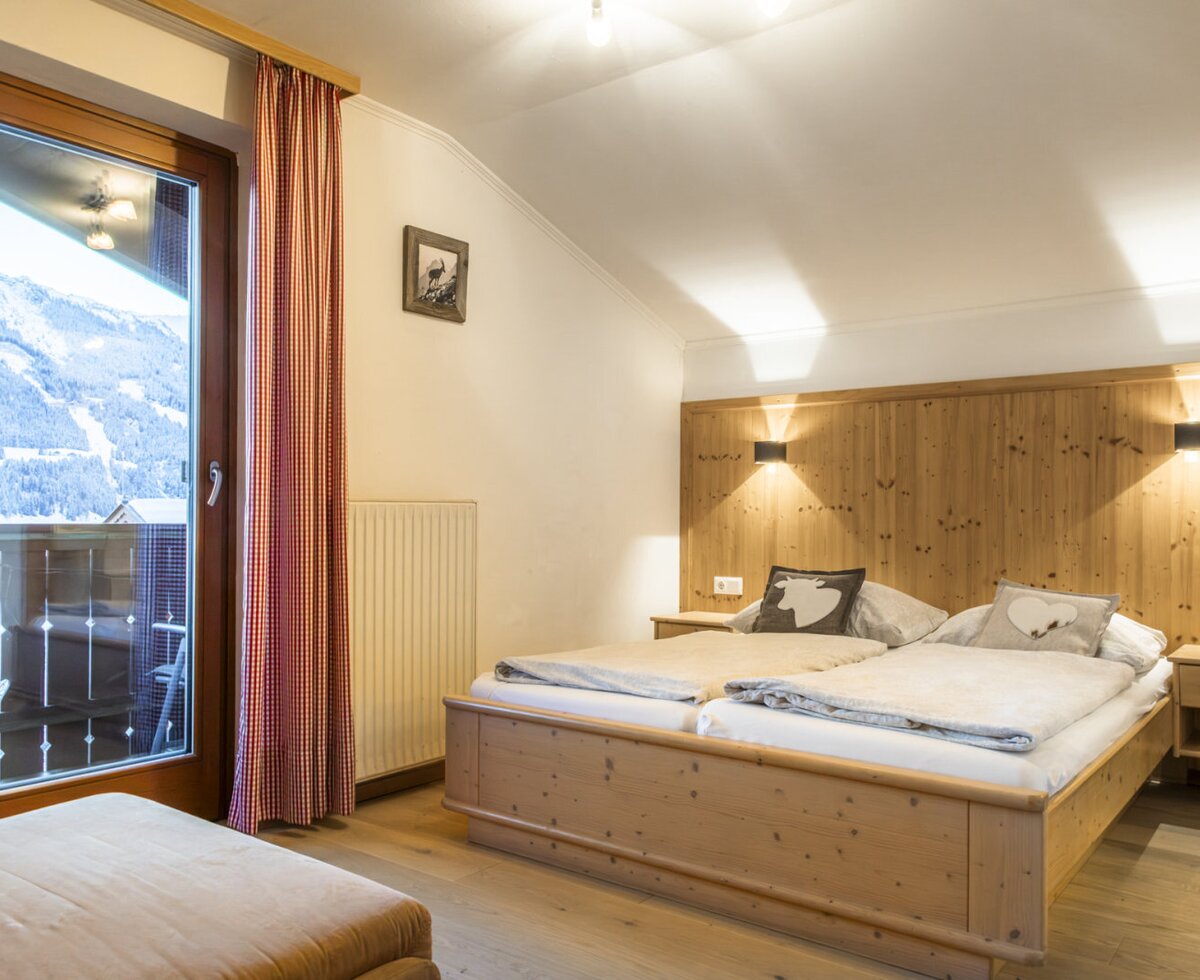 Double bedroom with wooden furnishings, balcony access, and mountain views.