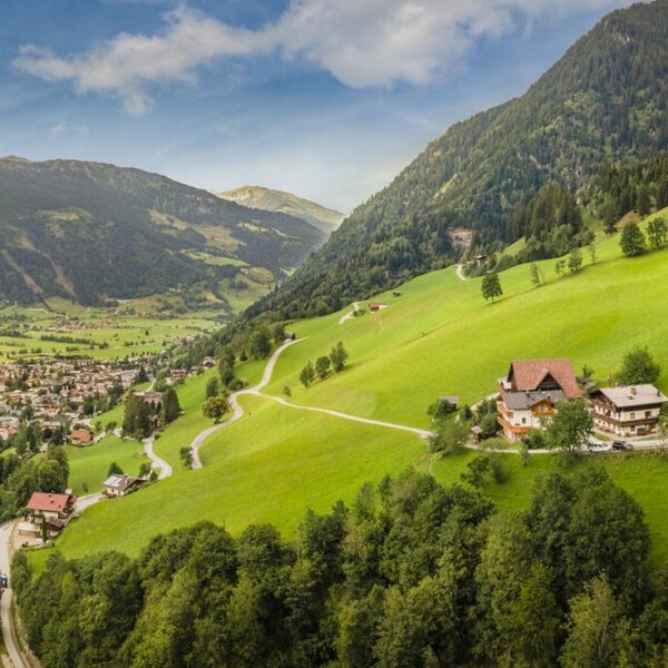 Scenic view of the farmhouse, nestled on lush green hills with a panoramic vista over the surrounding valley.