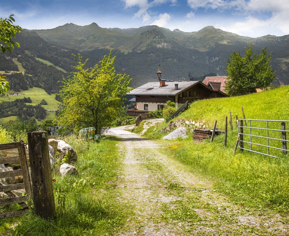 The idyllic farmhouse nestled in lush green meadows with scenic views of the surrounding mountains.