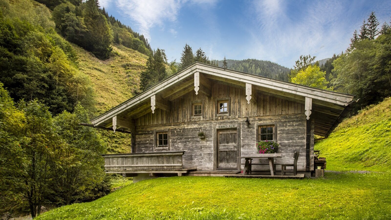 The rustic mountain hut  built in traditional wood style, surrounded by a lush green mountain meadow.