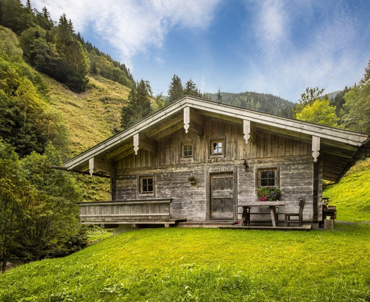 The rustic mountain hut  built in traditional wood style, surrounded by a lush green mountain meadow.