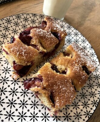Freshly baked cake with powdered sugar at the farmhouse, served with a glass of milk.
