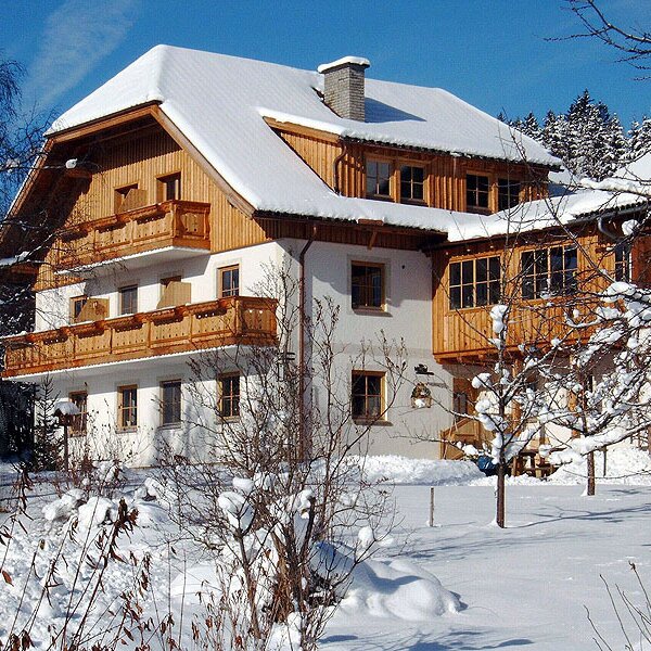 The Farm House exterior, featuring wooden balconies and a snow-covered roof in a winter setting.