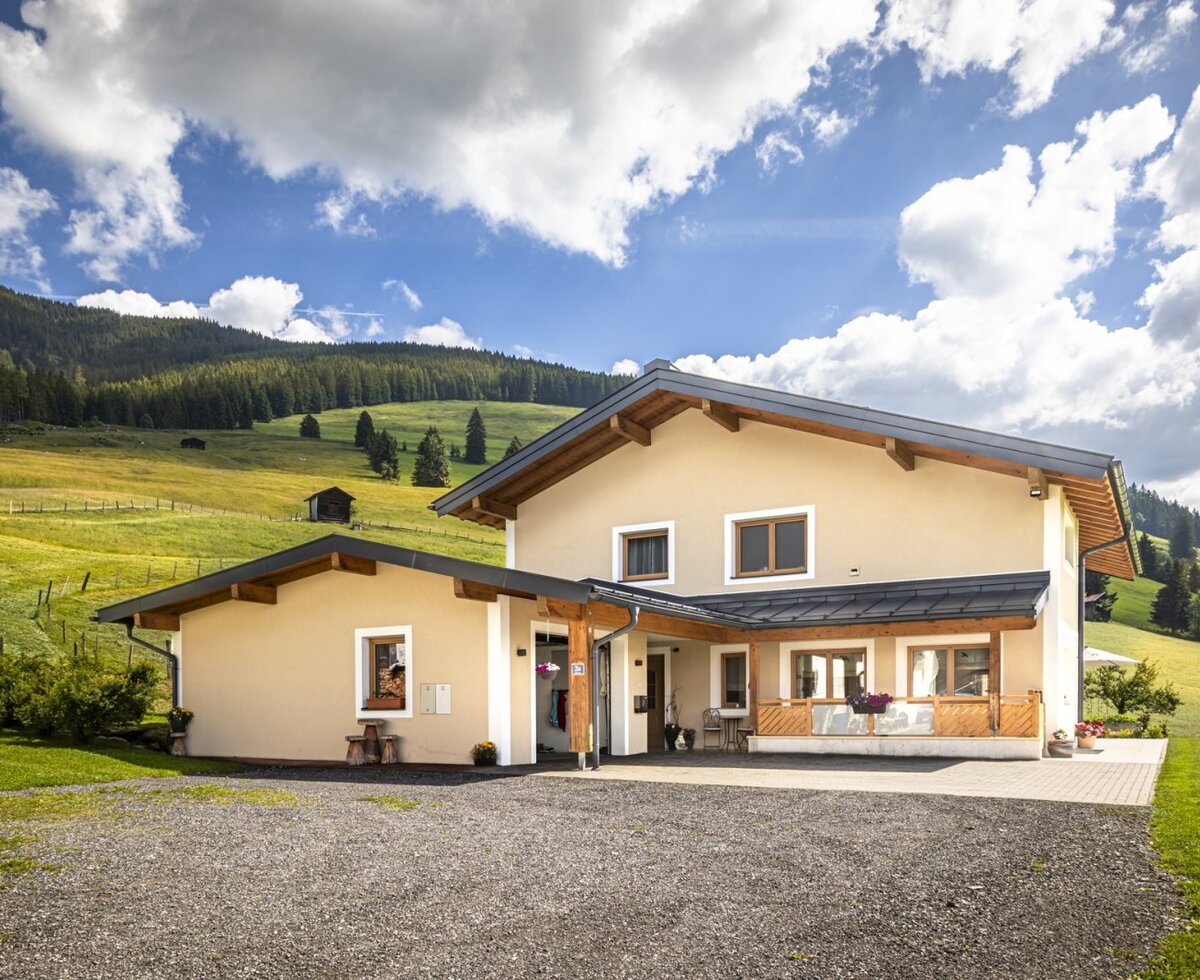 An inviting Bed and Breakfast set against lush green hillsides under a bright, sunny sky.