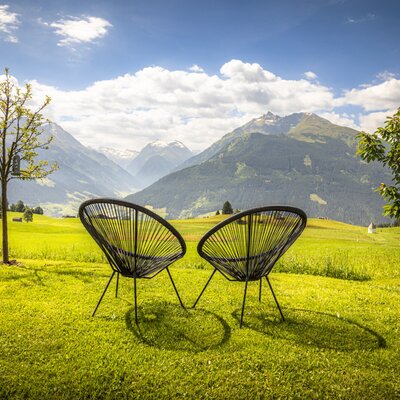 The bed and breakfast's inviting lawn featuring modern Acapulco chairs and a stunning panoramic view of the surrounding mountains.