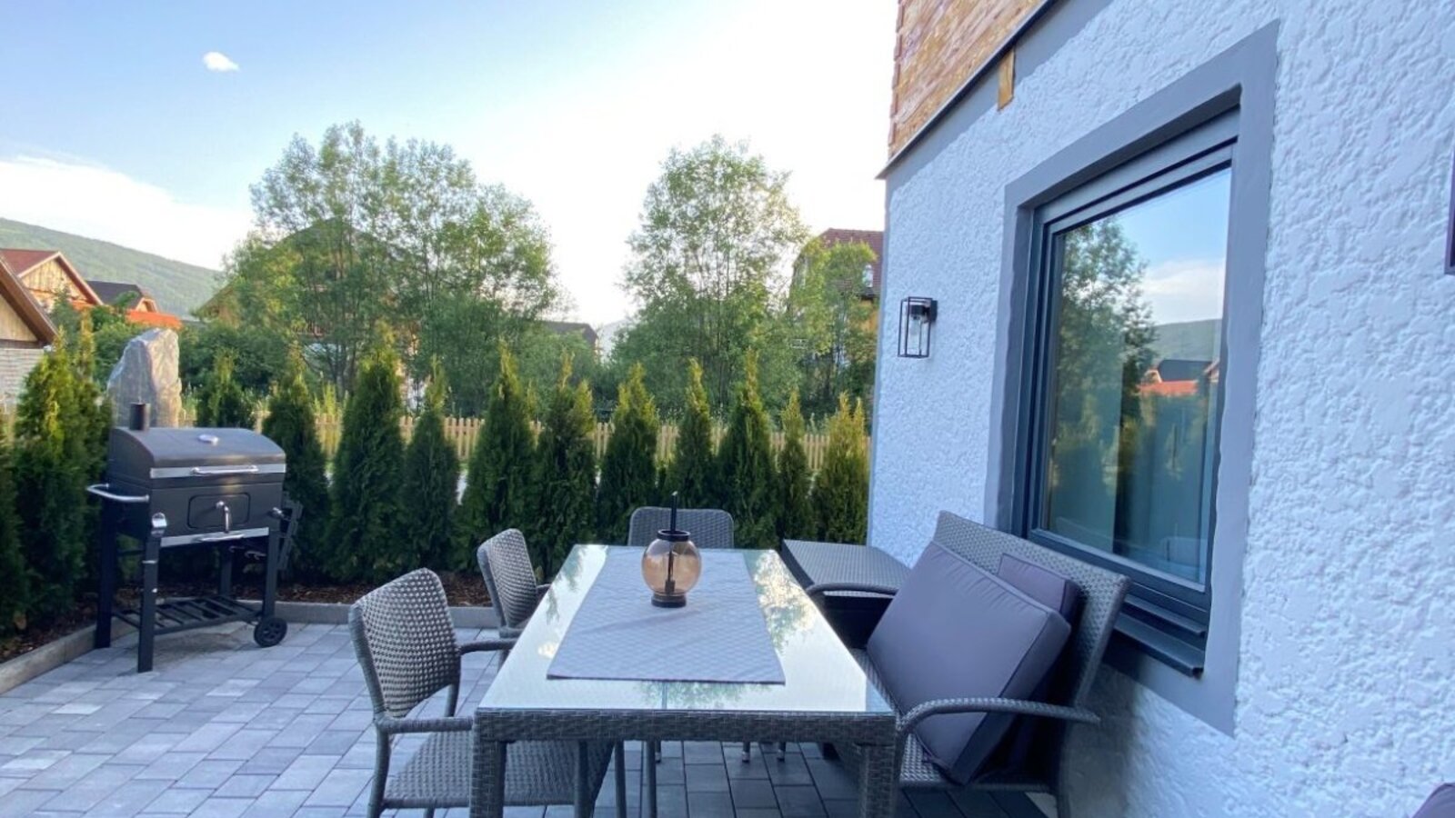 Outdoor paved patio at the farmhouse, featuring a dining table with chairs and a barbecue grill.