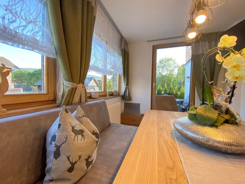 Dining area in the Farm House featuring a wooden table, bench seating, and a glass door leading to an outdoor space.