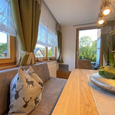 Dining area in the Farm House featuring a wooden table, bench seating, and a glass door leading to an outdoor space.