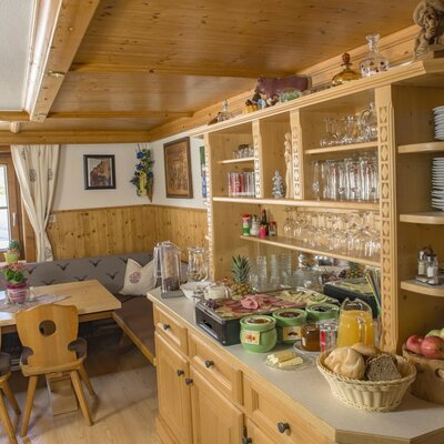The dining area in the Farm House features a breakfast buffet, wooden cabinetry, and a table with bench seating.