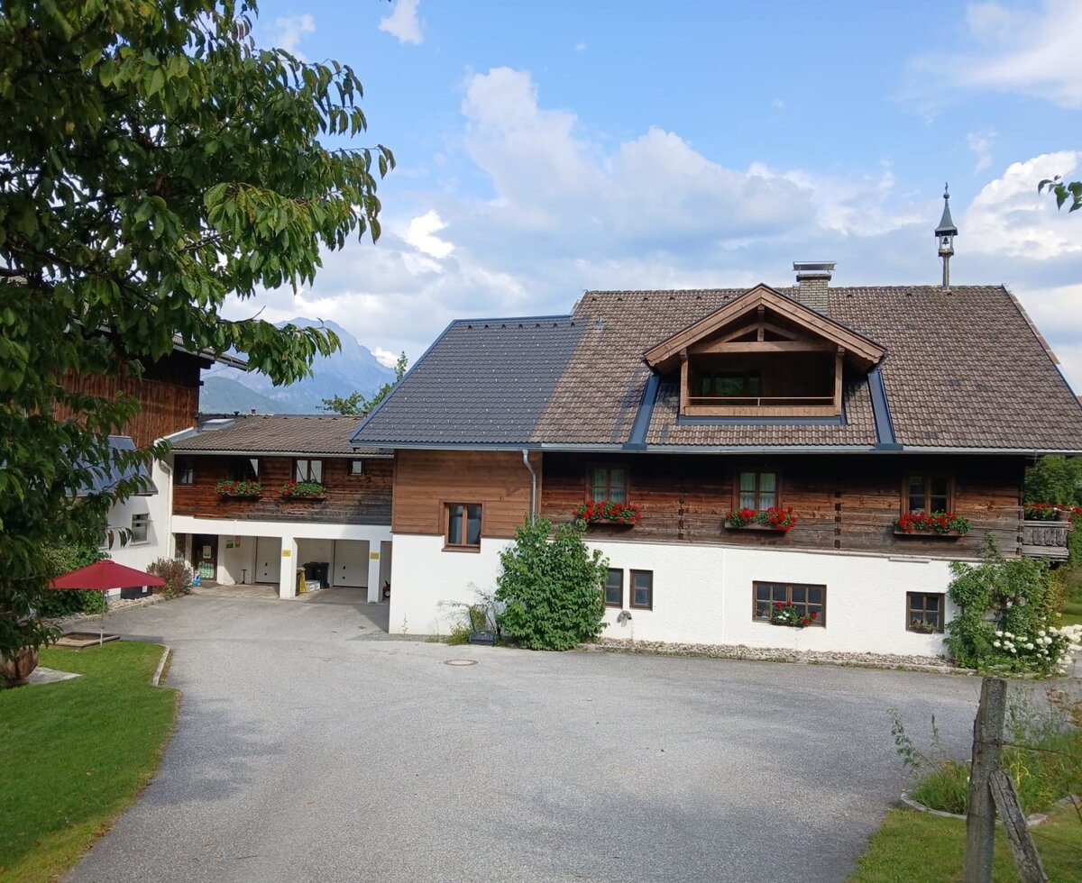 The inviting Hinterburghof farmhouse featuring a traditional wooden facade and flower-filled window boxes.