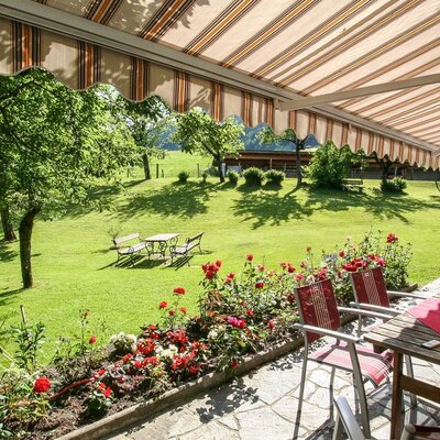 The Bauernhof's inviting terrace with a shading awning and views over the spacious, green lawn.