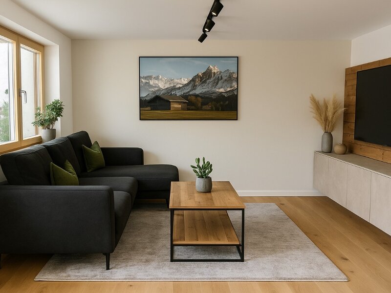 The living room of the Bed and Breakfast features a dark L-shaped sofa, a wooden coffee table, and a television.