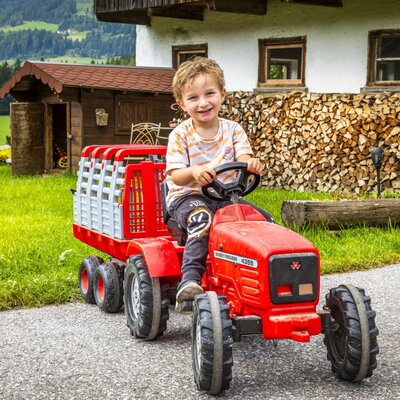 A child on a red pedal tractor with a trailer at the Bed and Breakfast.