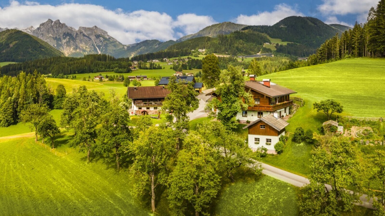 The Bed and Breakfast, featuring traditional buildings, surrounded by green meadows and mountains.