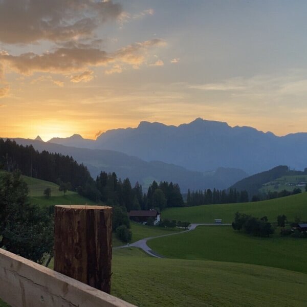 View of the sunset over a mountainous landscape with green fields and houses from the Bed and Breakfast.