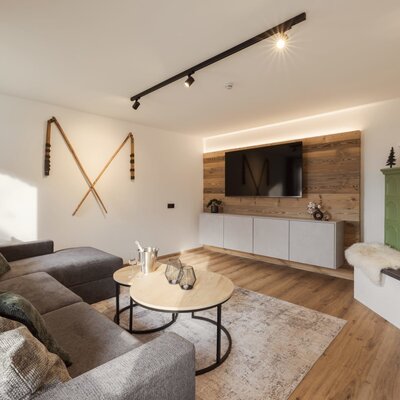 Living area in the Bed and Breakfast featuring a large sectional sofa, a wall-mounted TV, and a traditional tiled stove.