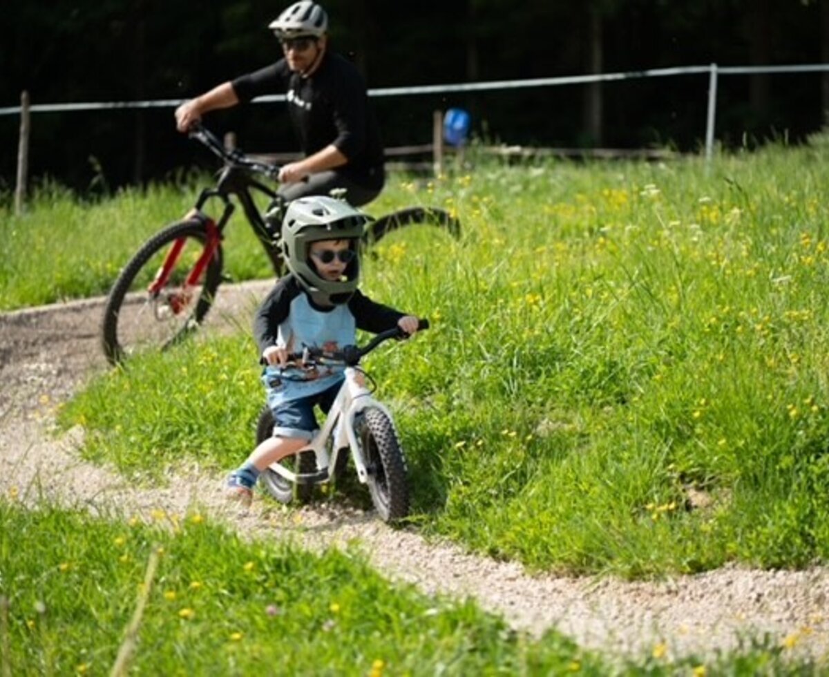 Cycling for children and adults on the farmhouse grounds, featuring a gravel path and green surroundings.