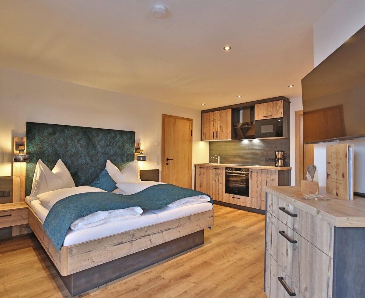 Guest room in the Farm House featuring a double bed, an integrated kitchenette, and a wall-mounted TV.