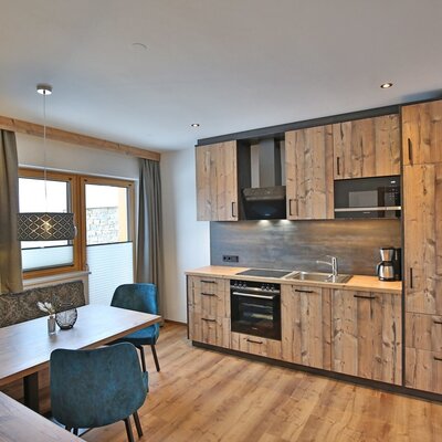 Kitchen and dining area in the Farm House with wooden cabinets, an oven, microwave, coffee maker, and a dining table with bench and chairs.