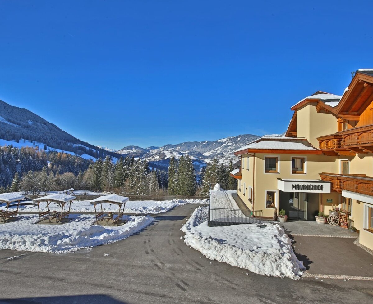 The inviting Maurachhof farmhouse surrounded by a scenic, snow-covered winter landscape with mountain views.