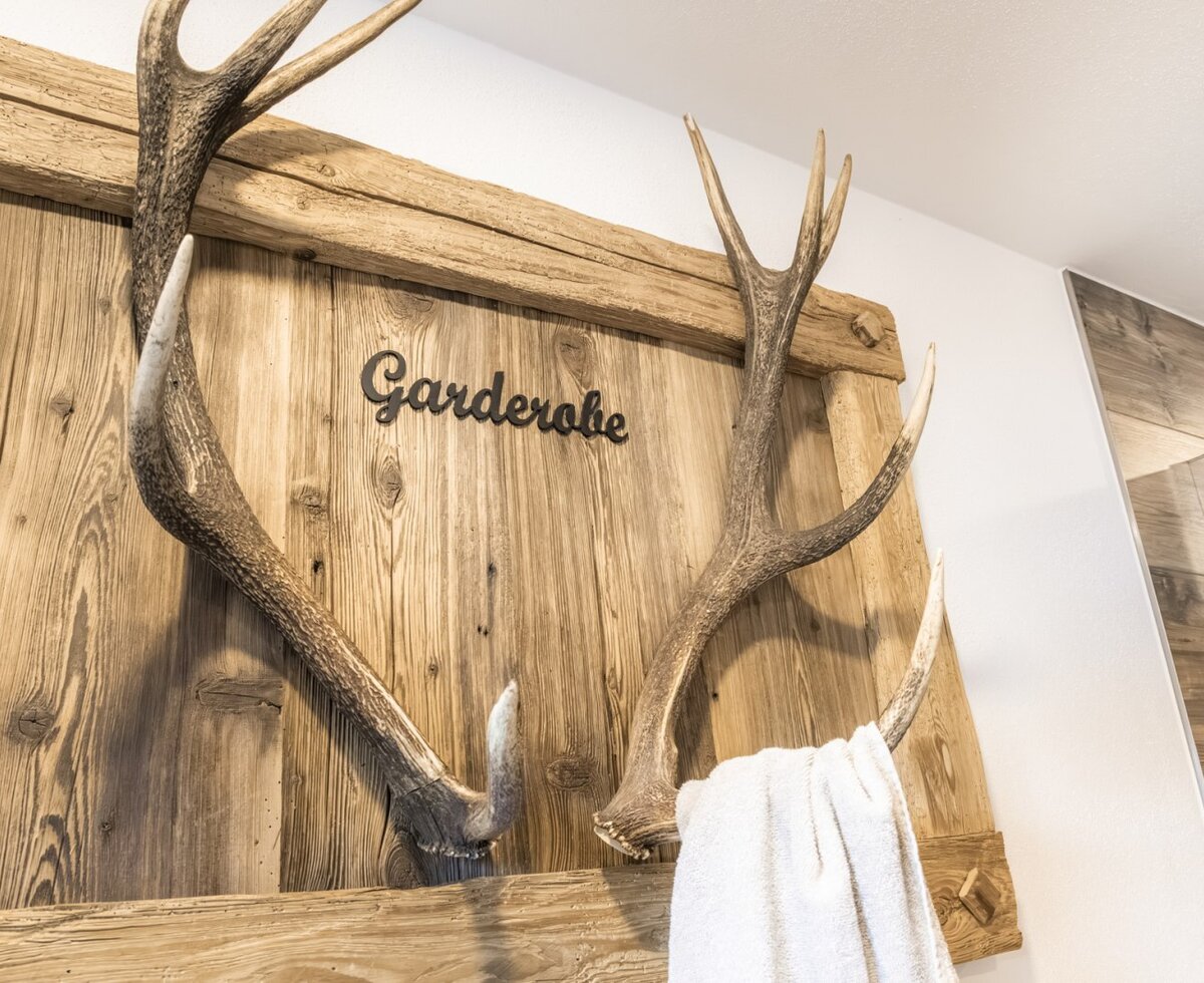 Wooden coat rack with antlers and a 'Garderobe' sign.