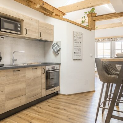 Modern kitchen  with microwave, coffee machine, oven, and a breakfast bar with stools.