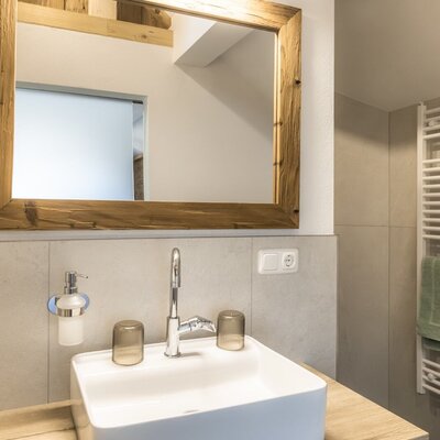 Bathroom with a sink, wooden-framed mirror, hairdryer, and towel warmer.