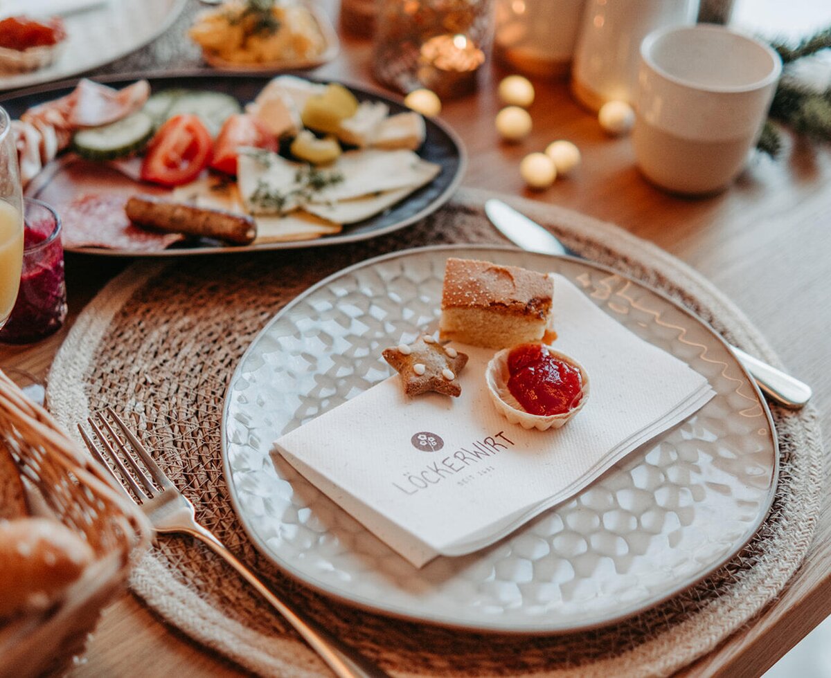 A set breakfast table at the farmhouse with a selection of pastries, cold cuts, cheese, and fresh juice.
