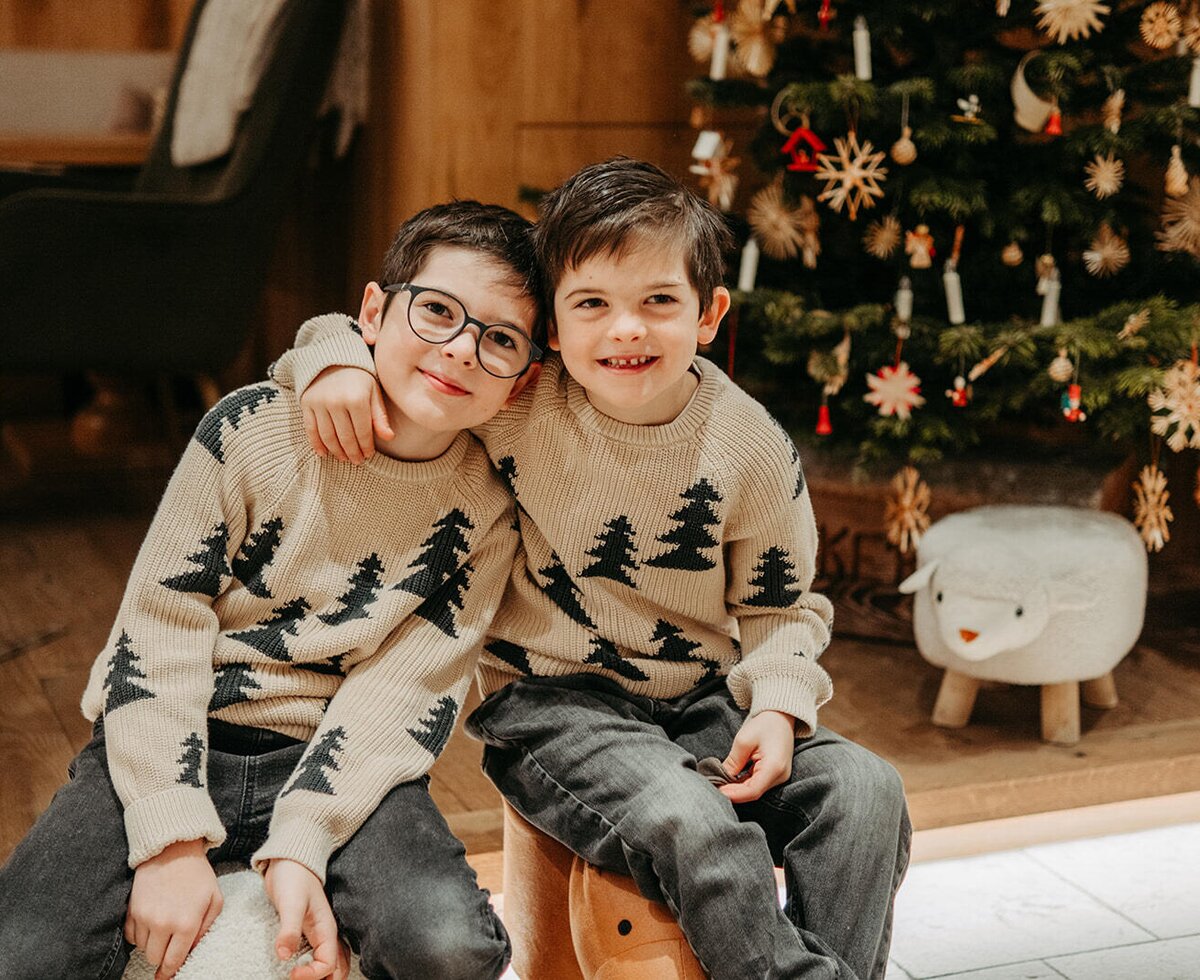 Two children smiling in front of a Christmas tree at the farmhouse, offering a family-friendly environment.