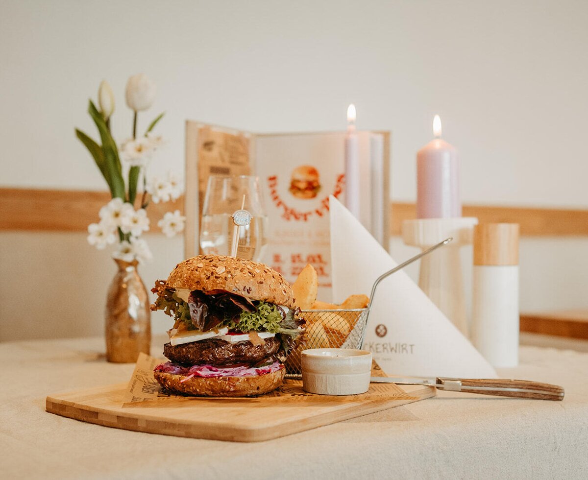 Burger with fries and dip, served on a wooden board in the Bauernhof's dining area.