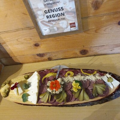 A platter of regional cold cuts and cheeses, showcasing products from the Grossarltal 'Genuss Region' at the farmhouse.