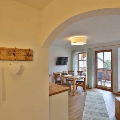 Living and dining area with a dining table, television, and balcony access.