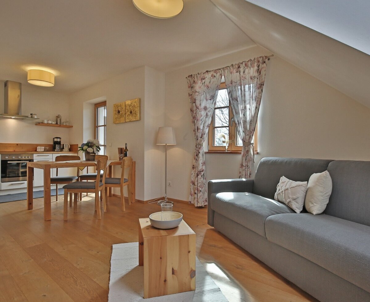 The open-plan living area of the apartment, featuring a fully equipped kitchen, dining space, and a sofa.