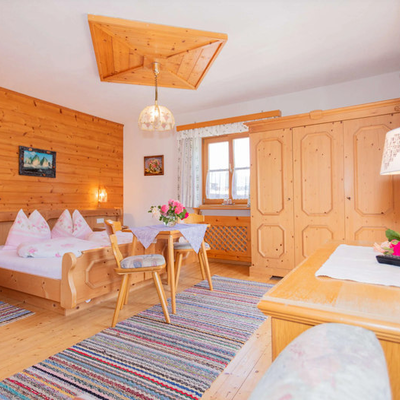 Bedroom in the Bed and Breakfast featuring a wooden double bed, dining table, wardrobe, and window.