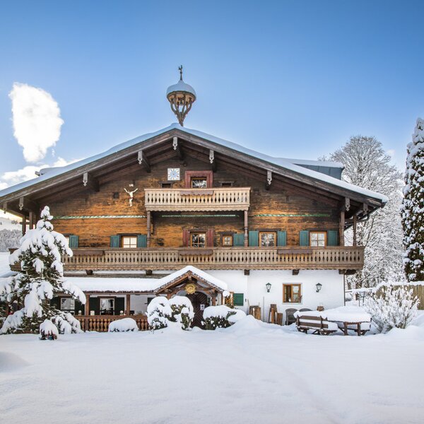 The Farm House exterior with traditional wooden balconies, covered in snow during winter.